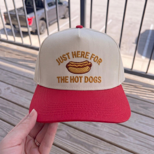Retro baseball cap with hot dog embroidery, cream front with red brim, wooden background