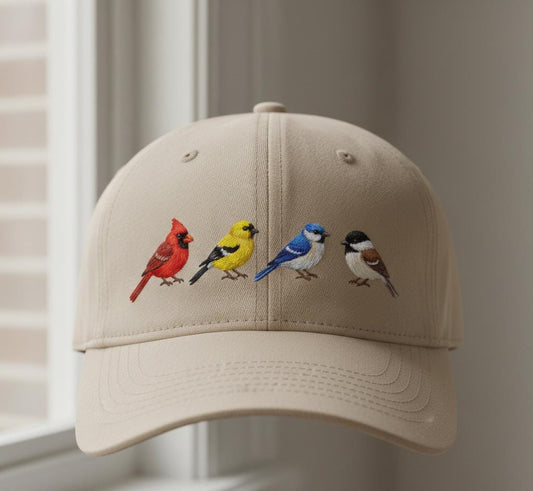 Beige cap with colorful embroidered birds design displayed by a window