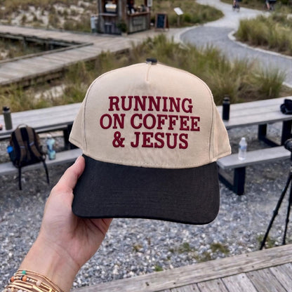 Unique baseball cap with 'Running on Coffee & Jesus' slogan, beige and black design, outdoors setting